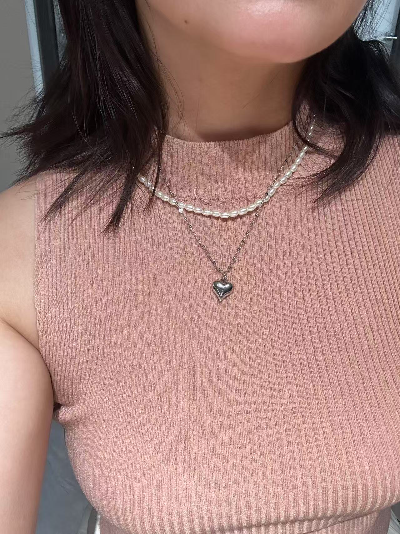 On-neck shot, layered silver necklace with pearl accent and heart charm, water resistant