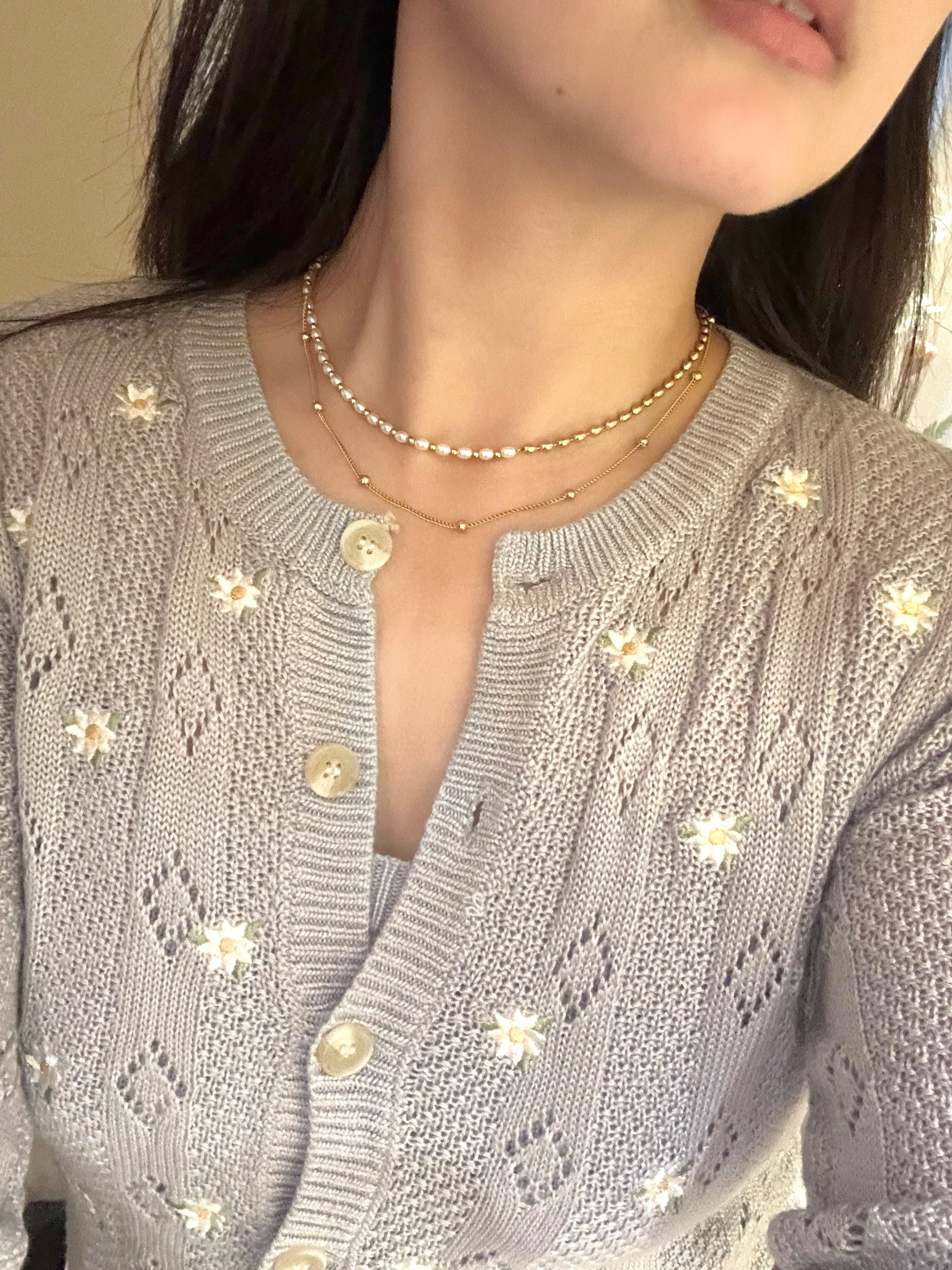 On neck: double-chained gold necklace with built-in stacking effect, nickel safe